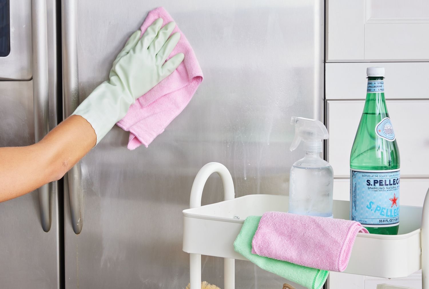 Cleaning a stainless sink with gloves and spray bottle